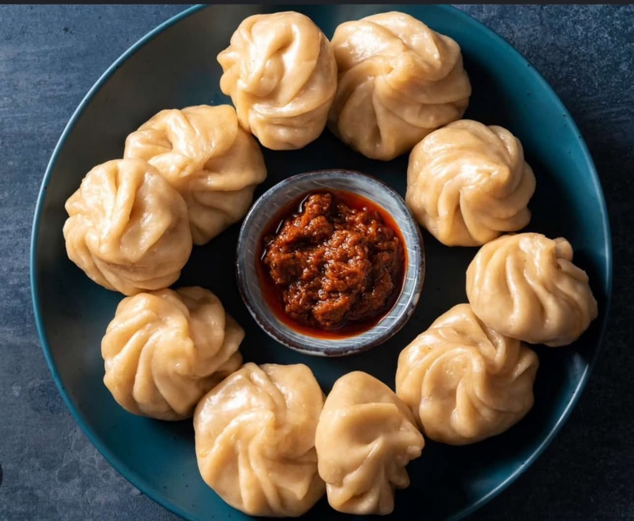 Handgemachte Momo von MomoGo mit tibetischem Chutney auf einem dunklen Teller