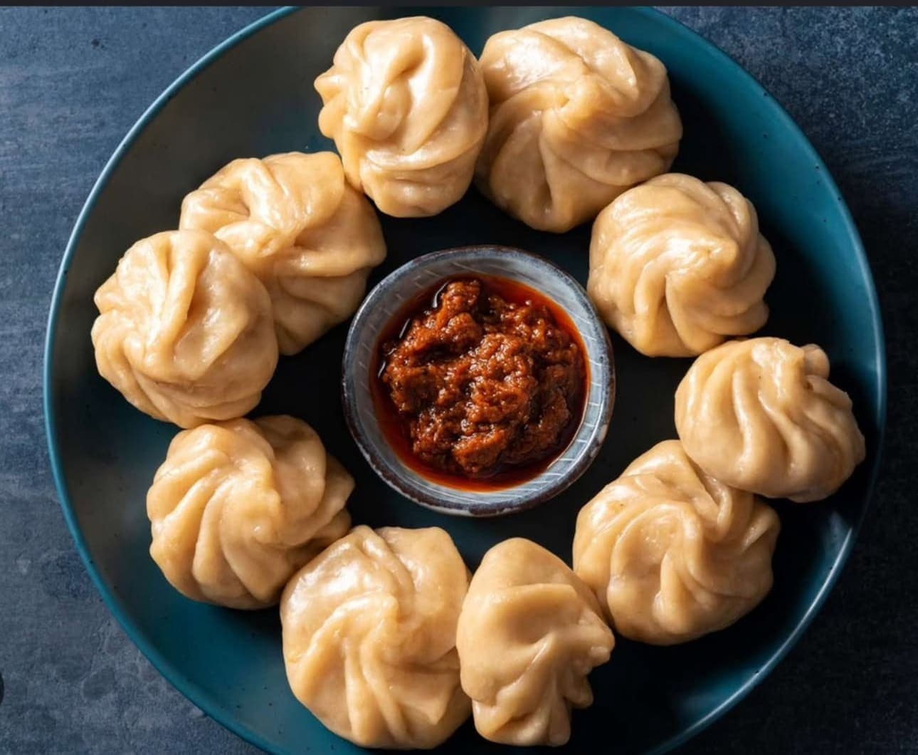 Handgemachte Momo von MomoGo mit tibetischem Chutney auf einem dunklen Teller